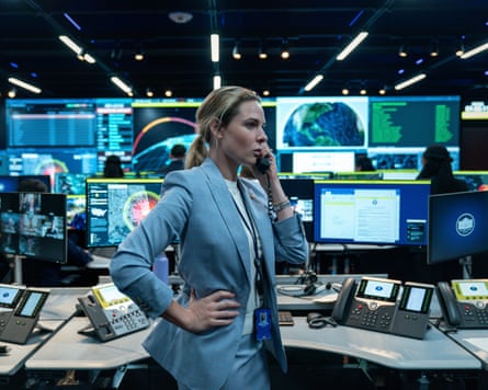 Scene from the film. A woman in a suit on the phone in a room full of computer screens