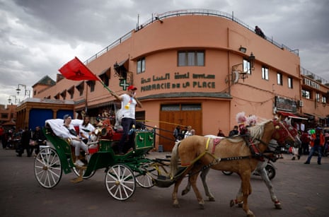 A man on a horse drawn carriage waves a Morocco flag in Marrakech ahead of the France v Morocco semi-final in Qatar.