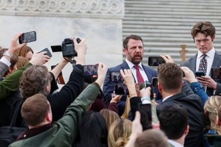 a man speaks to a crowd of people holding up their phones to record him
