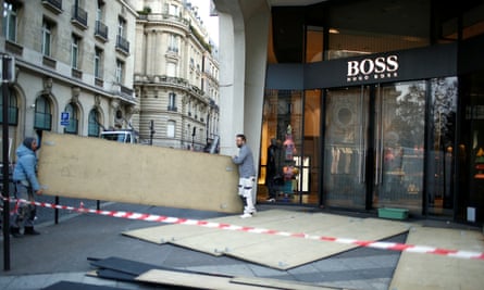Workmen remove protective wood panels outside a store in central Paris on Sunday