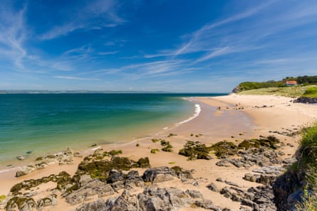 A nearly deserted soft sand beach with turquoise water and blue skies