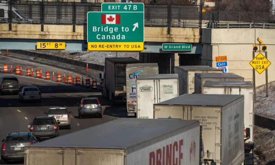 A long line of semi-trailer trucks line up along northbound I-75 in Detroit as the Ambassador Bridge entrance is blocked off for travel to Canada.