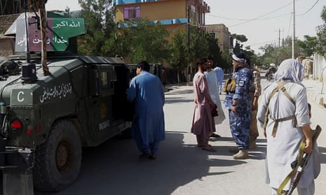 Afghan security personnel stand guard along a road in the western city of Qala-i- Naw.