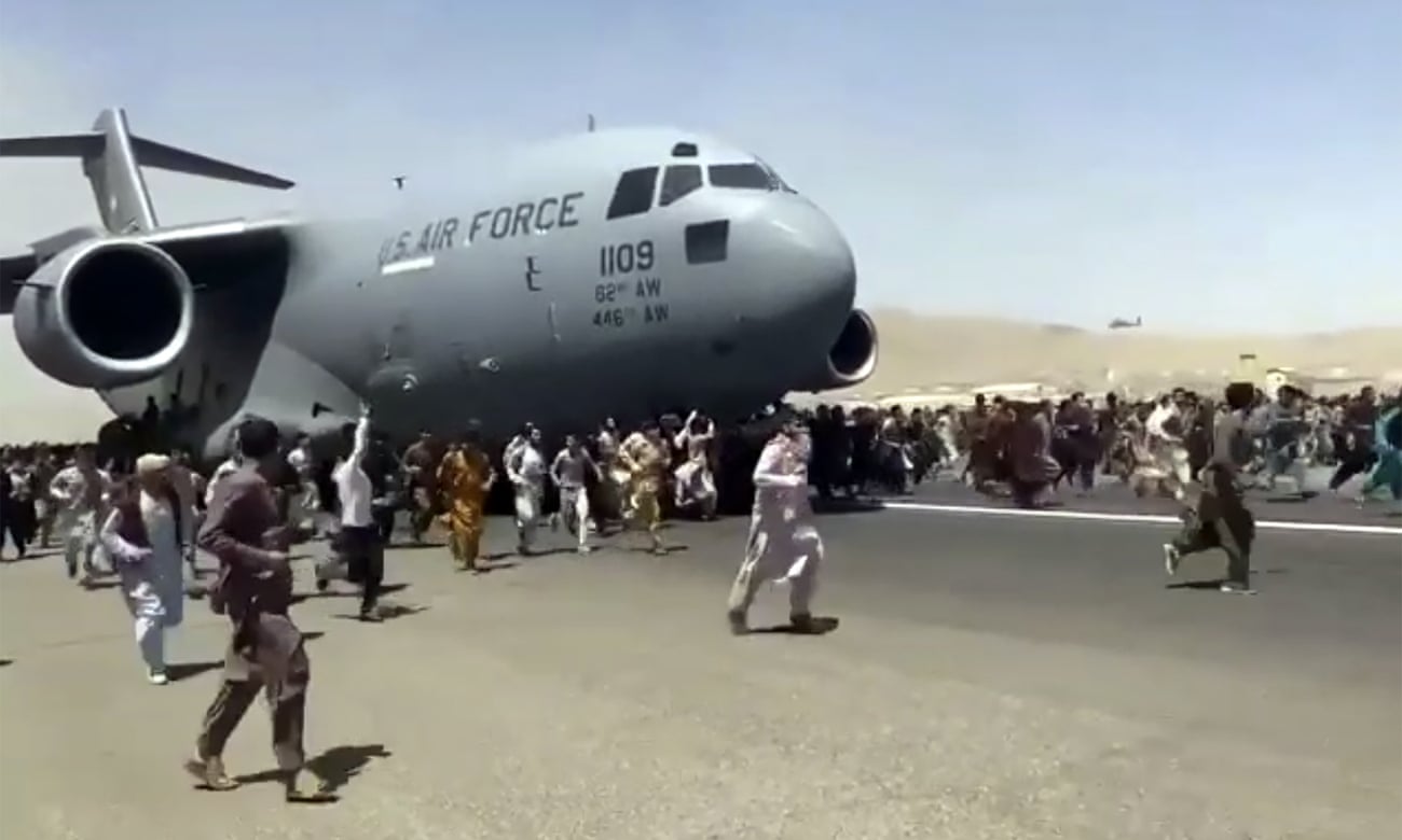 افغان ها در کنار یک هواپیمای ترابری نیروی هوایی ایالات متحده که می خواهد از کابل، افغانستان بلند شود، می دوند.