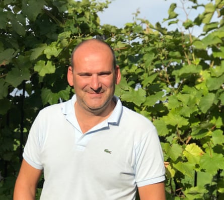 A man standing in a vineyard with plants in the background
