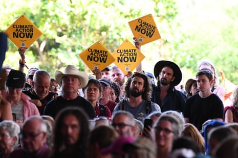 Protesters hold signs as Albanese speaks at the Woodford folk festival in Queensland.