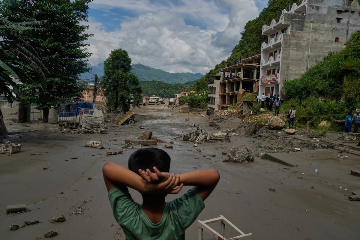A child looks at the damage caused by the flooding along the Trishuli River