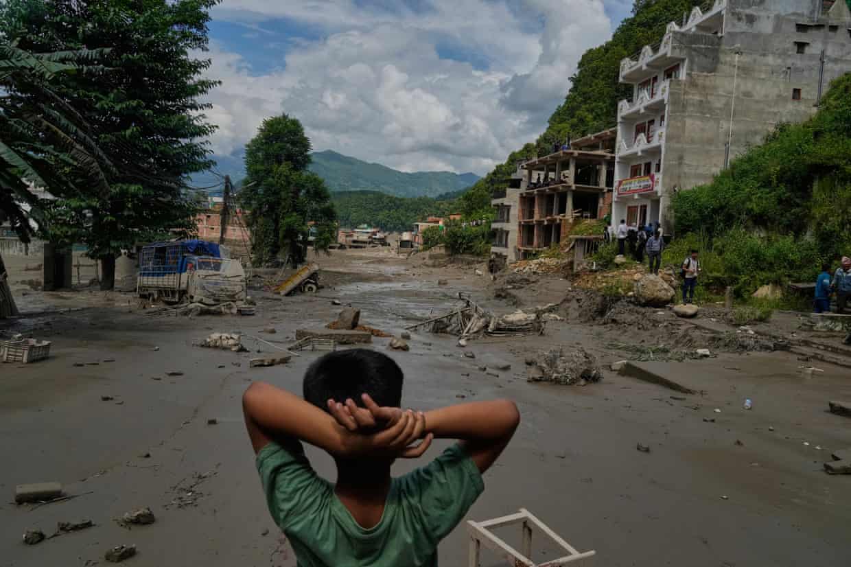A child looks at the damage caused by the flooding along the Trishuli River