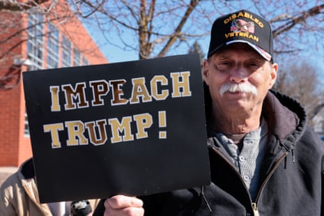 A man holds a sign reading "Impeach Trump" as he takes part in the "No Kings" national day of protest in Howell, Michigan, on March 28, 2026.