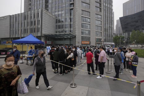 Residents and office workers wearing face masks line up for mass coronavirus testing outside a commercial office complex at the central business district in Beijing.