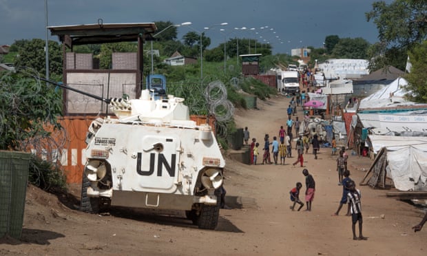 Civilians at a UN base in Juba walk by a watchtower manned by UN peacekeepers.