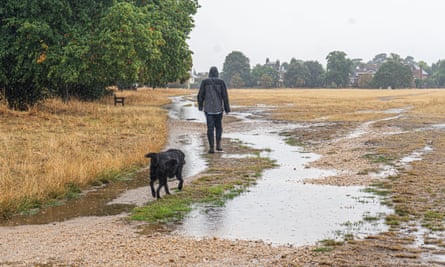 A man walks his dog on a waterlogged Wimbledon common in south-west London on Thursday