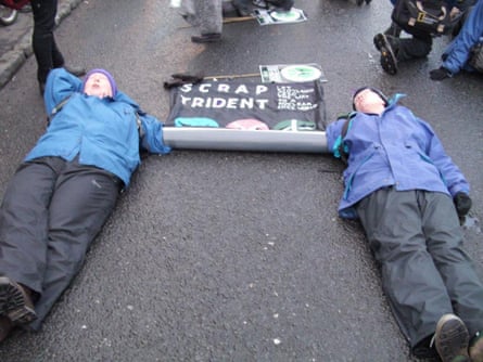Margaret Bremner and Sheila MacKay lie in the road with a Scrap Trident poster
