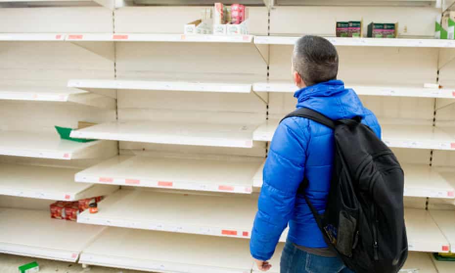 A shopper in front of empty rice and tinned goods shelves at a Sainsbury’s. 