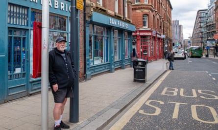 John Walker stands at a bus stop