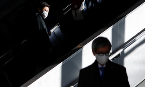 Passengers in a train station in Tokyo, Japan on Friday. Two men in suits wear masks.