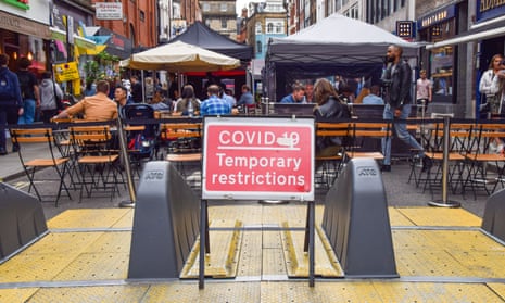 Covid restrictions sign seen by outdoor restaurant tables in Old Compton Street, Soho, London.