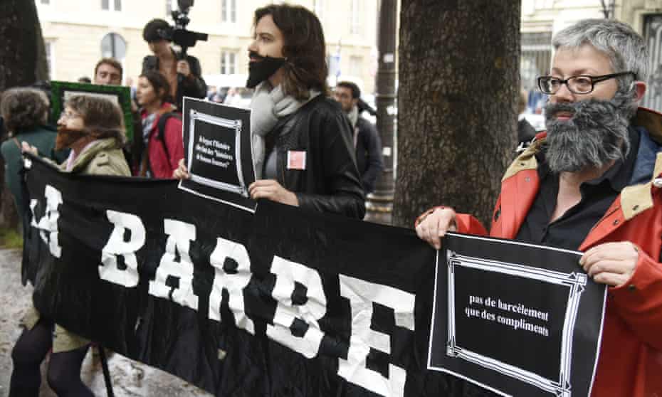 Women hold a banner reading ‘la barbe’ at a protest against harassment outside the National Assembly