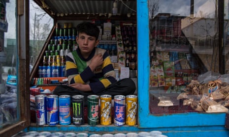 Mustafa, 13, sits in his cousin’s shop, selling dozens of different kinds of energy drinks.