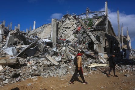 People walk past the rubble
