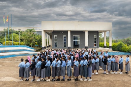 A crowd of girls in school uniform line up outside a school