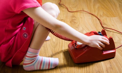 A young girls answers a vintage red telephone