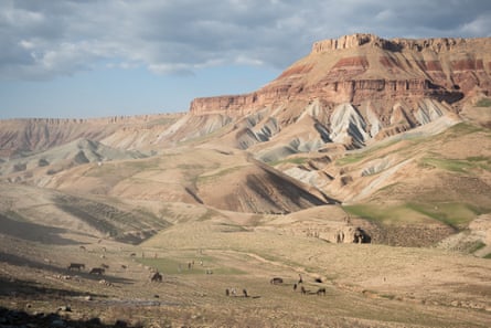 Rolling hills of dry grass rising to a rocky plateau.