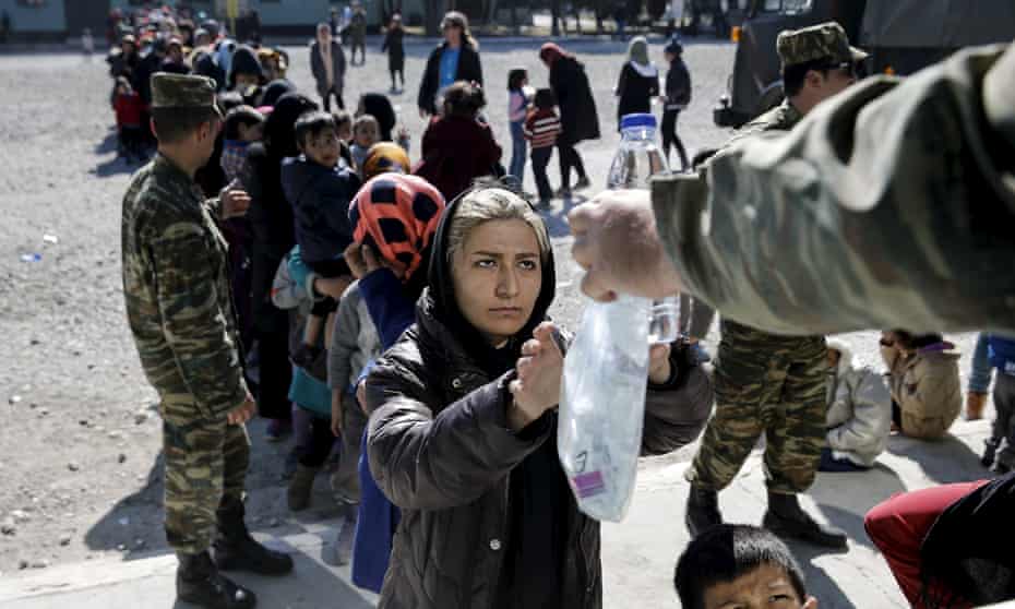 A woman receives food and water at a relocation camp in Schisto, a suburb of Athens.