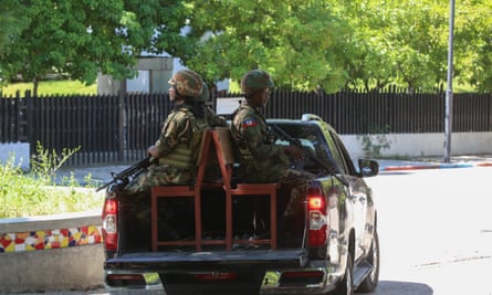 Soldiers with guns ride on vehicle