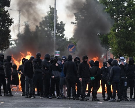 Young men in all black, hoods up with their faces covered