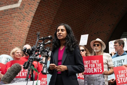 a women speaking in front of a microphone with people behind her