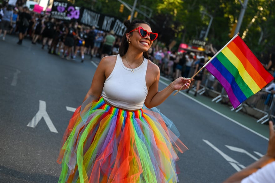 A woman smiles waving a Pride flag at the 30th Annual New York City Dyke March on Saturday in New York City.
