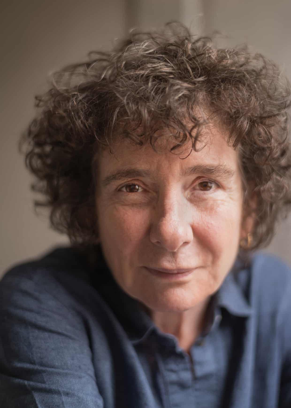 Close up of a woman with dark curly hair and a blue shirt