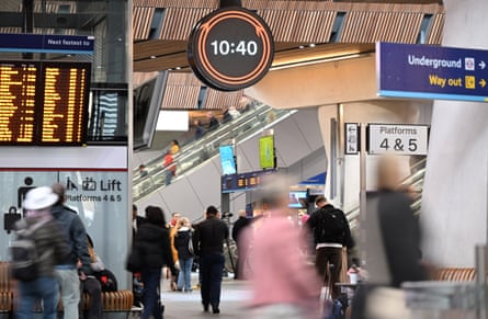 Commuters walk under the clock in London Bridge station