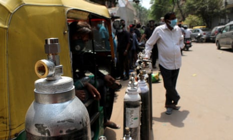 People stand in a queue with their oxygen cylinders outside a shop to get them refilled in Delhi.