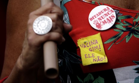 A demonstrator with pins on her shirt with messages that read in Portuguese “Vaccine Yes, not him” and “Dictatorship never again,” joins a protest against the government’s response in combating COVID-19 and demanding the impeachment of Brazil’s President Jair Bolsonaro, in Brasilia, Brazil, Saturday, Feb. 21, 2021.