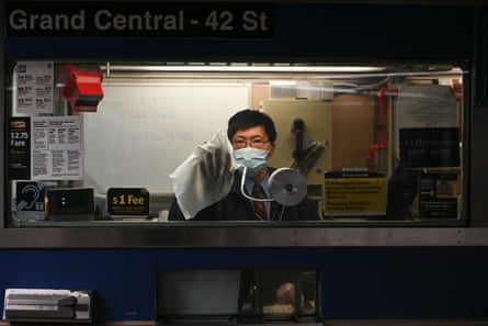 A transit worker wears a mask as he cleans the window of a booth in the Grand Central subway station.