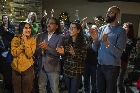Group of people stand in dimly lit room smiling and clapping