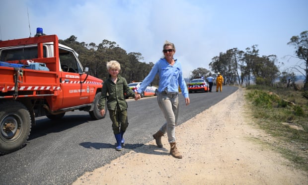Katie Rossington and her son Gus wait at a roadblock to get to their property as smoke from a large bushfire is seen outside Wytaliba, near Glen Innes, on Sunday