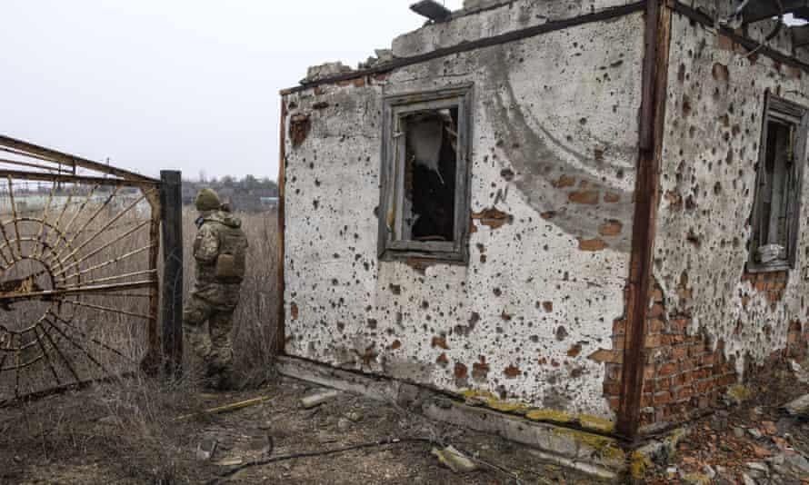 Un soldado ucraniano pasa frente a una casa abandonada en el frente.
