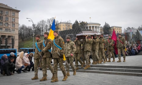 People kneel as Ukrainian servicemen carry the coffin of their comrade Oleh Yurchenko.