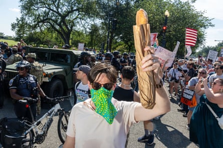 person holding baguette as a group of national guard members and people stand behind