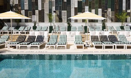 Swimming pool with stripy sun beds and umbrellas by the poolside