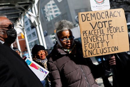 woman holds sign saying 'democracy - vote - peaceful people - Diversity, equity, inclusion'