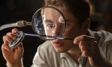 Gabriel LaBelle looking at a strip of celluloid under a magnifying glass