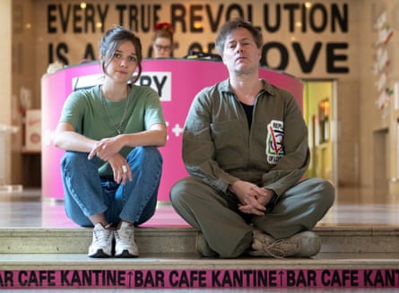 Servane Dècle and Milo Rau sitting on a step while looking at the camera