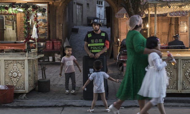 Uighur children pass a policeman
