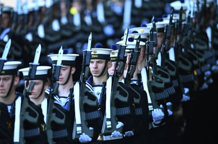 Members of the Irish navy in formation. They wear black and white hats, traditional striped sailor tops and white gloves, with what appear to be ceremonial bayonets across their shoulders.