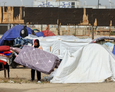 A woman holds a mattress next to her tent at a temporary encampment for displaced people in Beirut on Friday