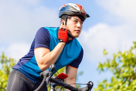 A young cyclist wearing helmet and ear buds